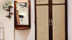A room with a wooden door with a woven pattern, a mirror on the wall, and a ceiling fan.