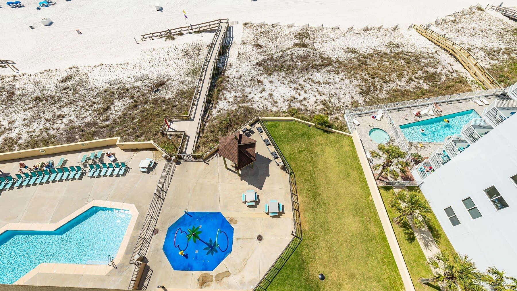 A resort with multiple swimming pools, a beach area, and a grassy lawn.
