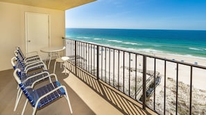 A balcony with a view of the beach, a door, and a table with chairs. - Phoenix I 1092 2 Bedroom Condo (Orange Beach)