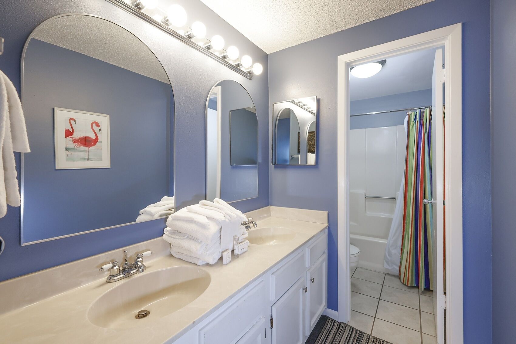 A bathroom with a double sink, a large mirror, and a shower curtain.