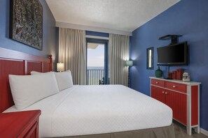 A hotel room with a large bed, a TV, a red dresser, and a view of the ocean. - Phoenix I 1145 2 Bedroom Condo (Orange Beach)