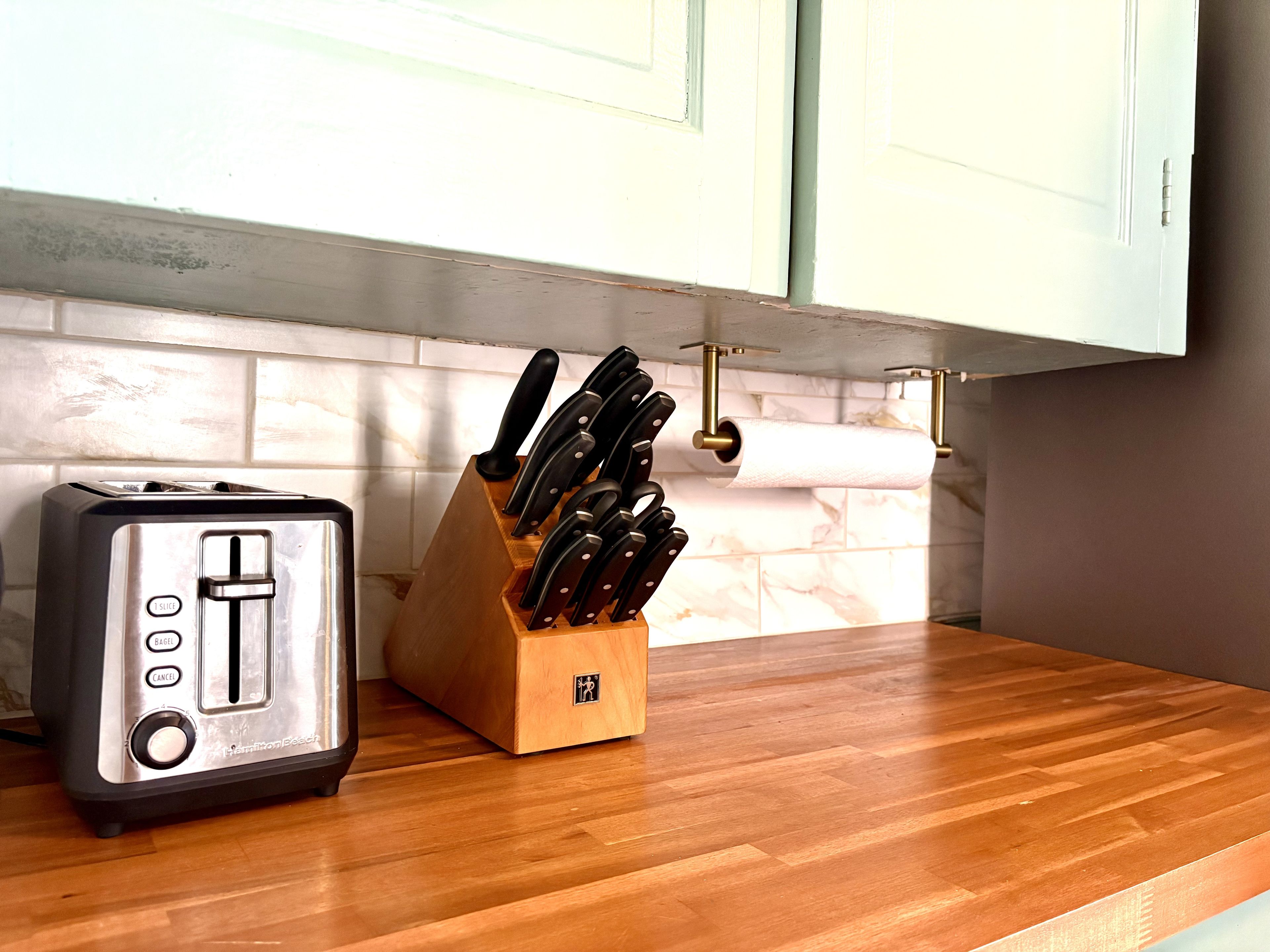 A kitchen with a toaster and a knife block on the counter.