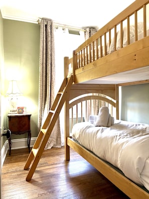 A bunk bed with a wooden ladder, a bedside table with a lamp, and a curtain. - Charming Victorian Duplex 4br Sleeps 10 3 Bedroom Home (Niagara Falls)