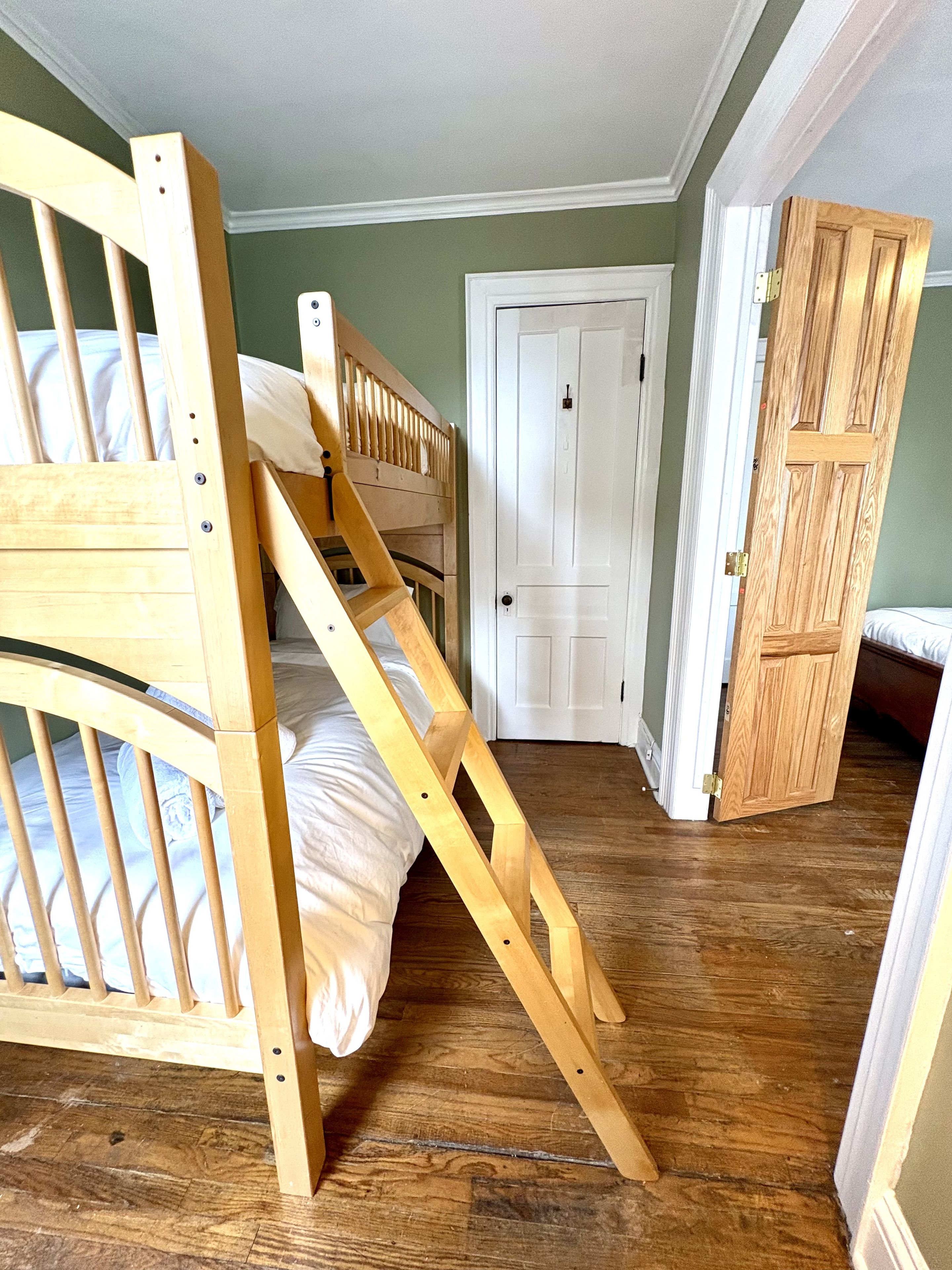 Ein Zimmer mit einem Etagenbett, einer Tür und einer Holztreppe.