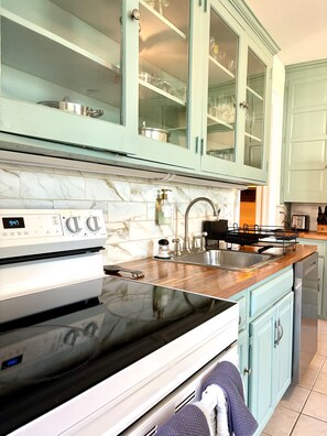 A kitchen with a white stove, a sink, and light blue cabinets. - Charming Victorian Duplex 4br Sleeps 10 3 Bedroom Home (Niagara Falls)