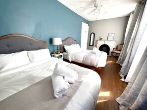Une chambre d’hôtel avec deux lits, un ventilateur de plafond, une cheminée et un miroir.