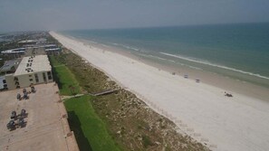 Ein Strand mit einem Gebäude links und freiem Blick auf den Ozean.
