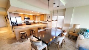 Una cocina moderna con una isla central, taburetes de bar y una mesa de comedor.