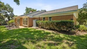 A residential house with a brick exterior, a covered patio with outdoor furniture, and a well-maintained lawn. - 1826 Highland Drive 3 Bedroom Home (Fernandina Beach)