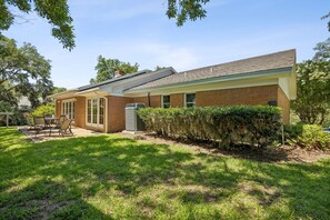A residential house with a brick exterior, a covered patio with outdoor furniture, and a well-maintained lawn. - 1826 Highland Drive 3 Bedroom Home (Fernandina Beach)