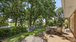 An outdoor patio with a table and chairs, surrounded by trees and a view of a water body. - 1826 Highland Drive 3 Bedroom Home (Fernandina Beach)