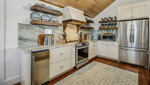 A kitchen with white cabinetry, a stainless steel refrigerator, a built-in oven, and marble countertops. - 733a And B Tarpon Avenue 6 Bedroom Home (Fernandina Beach)