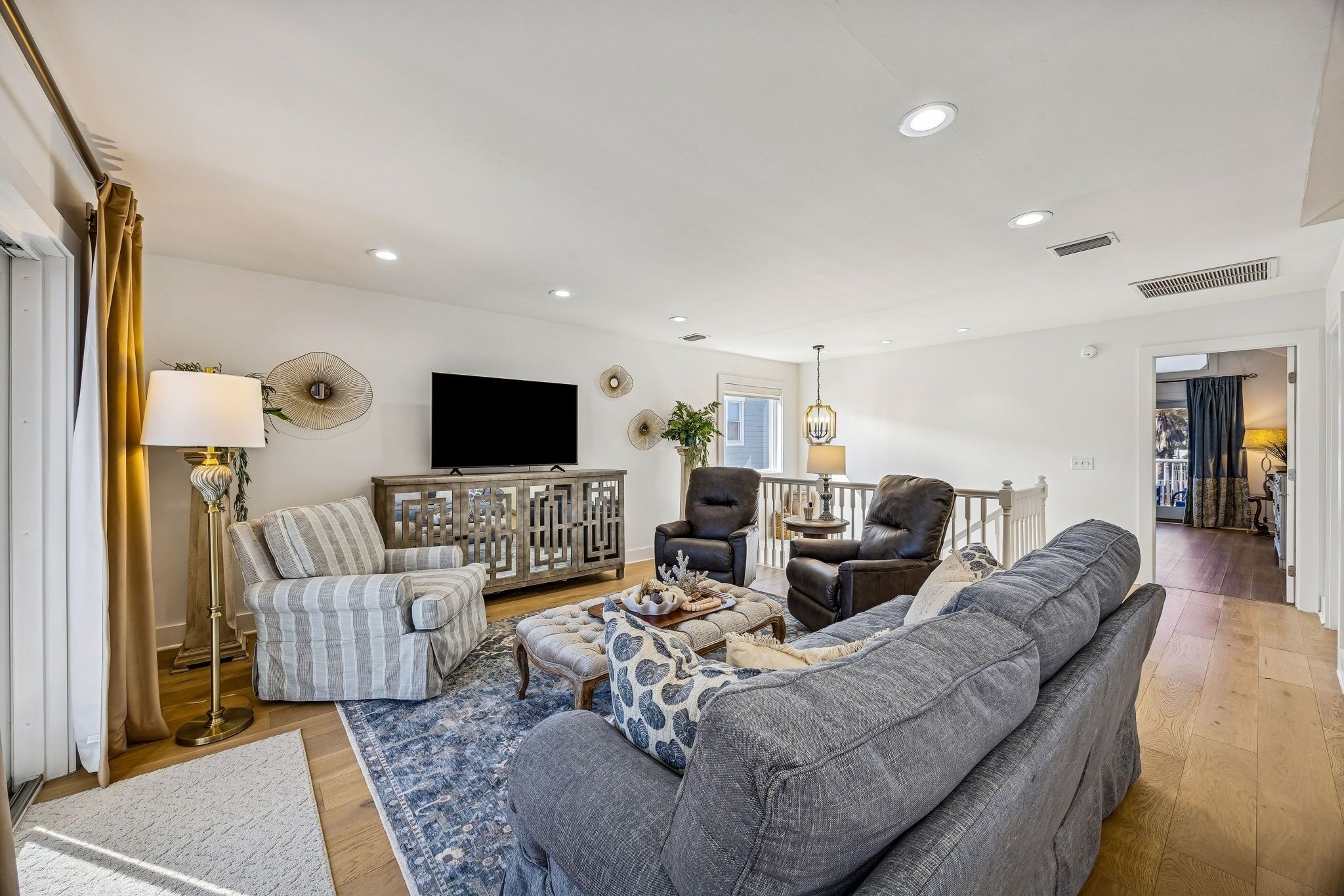 Una sala de estar moderna con un sofá, sillones, un televisor y objetos decorativos.