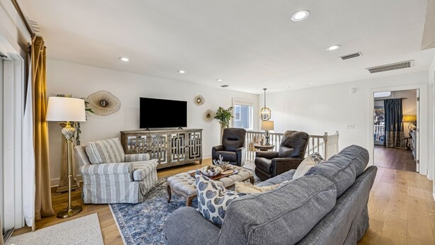 A modern living room with a sofa, armchairs, a TV, and decorative items. - 733a And B Tarpon Avenue 6 Bedroom Home (Fernandina Beach)