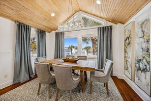 A dining area with a wooden table, four upholstered chairs, and a chandelier. - 733a And B Tarpon Avenue 6 Bedroom Home (Fernandina Beach)
