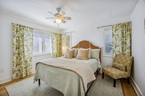 A bedroom with a bed, a chair, a ceiling fan, and curtains. - 733a And B Tarpon Avenue 6 Bedroom Home (Fernandina Beach)