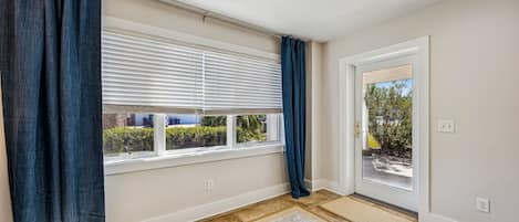 A room with a large window, a door, and a doormat.
