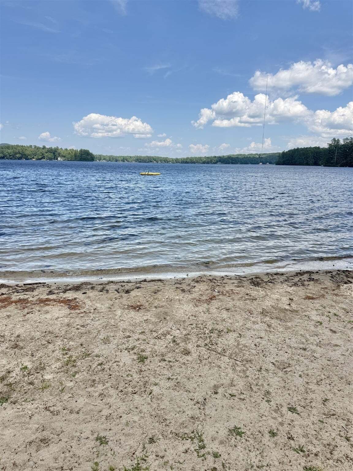 A beach with a sandy shore and a calm body of water.