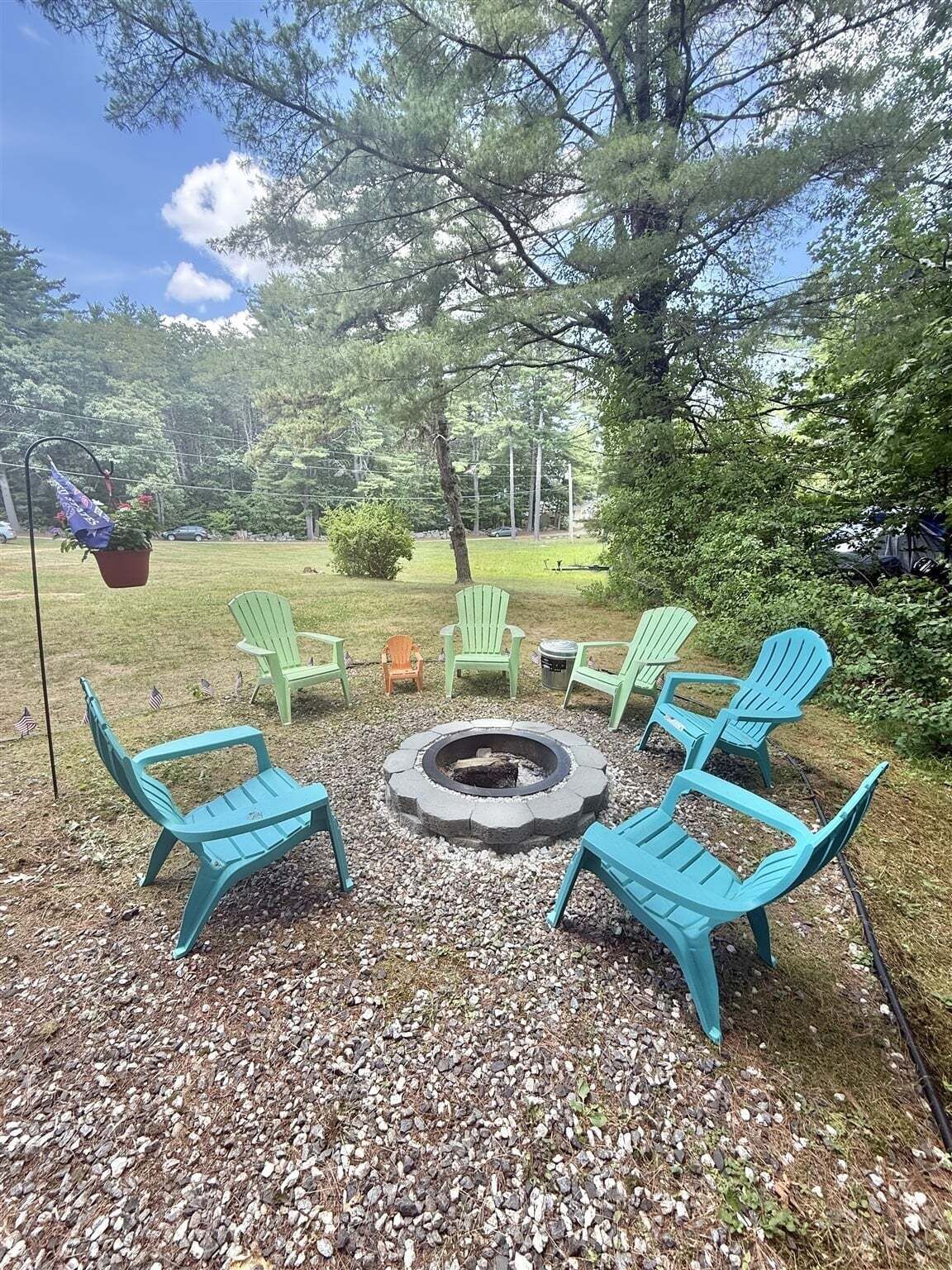 A fire pit surrounded by outdoor seating, with trees and a clear sky in the background.
