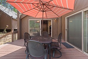 A patio with a table and chairs, an umbrella, and a sliding glass door. - 16 Pole House 2 Bedroom Home (Bend)