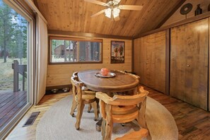 A wooden interior with a round table, chairs, a ceiling fan, and a window with blinds. - 16 Pole House 2 Bedroom Home (Bend)
