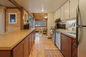 A modern kitchen with wooden cabinetry, a stainless steel refrigerator, and a built-in oven. - 16 Pole House 2 Bedroom Home (Bend)