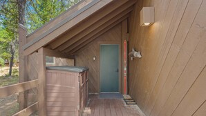 Eine Holzterrasse, die zu einer Tür mit einer kleinen Veranda führt.