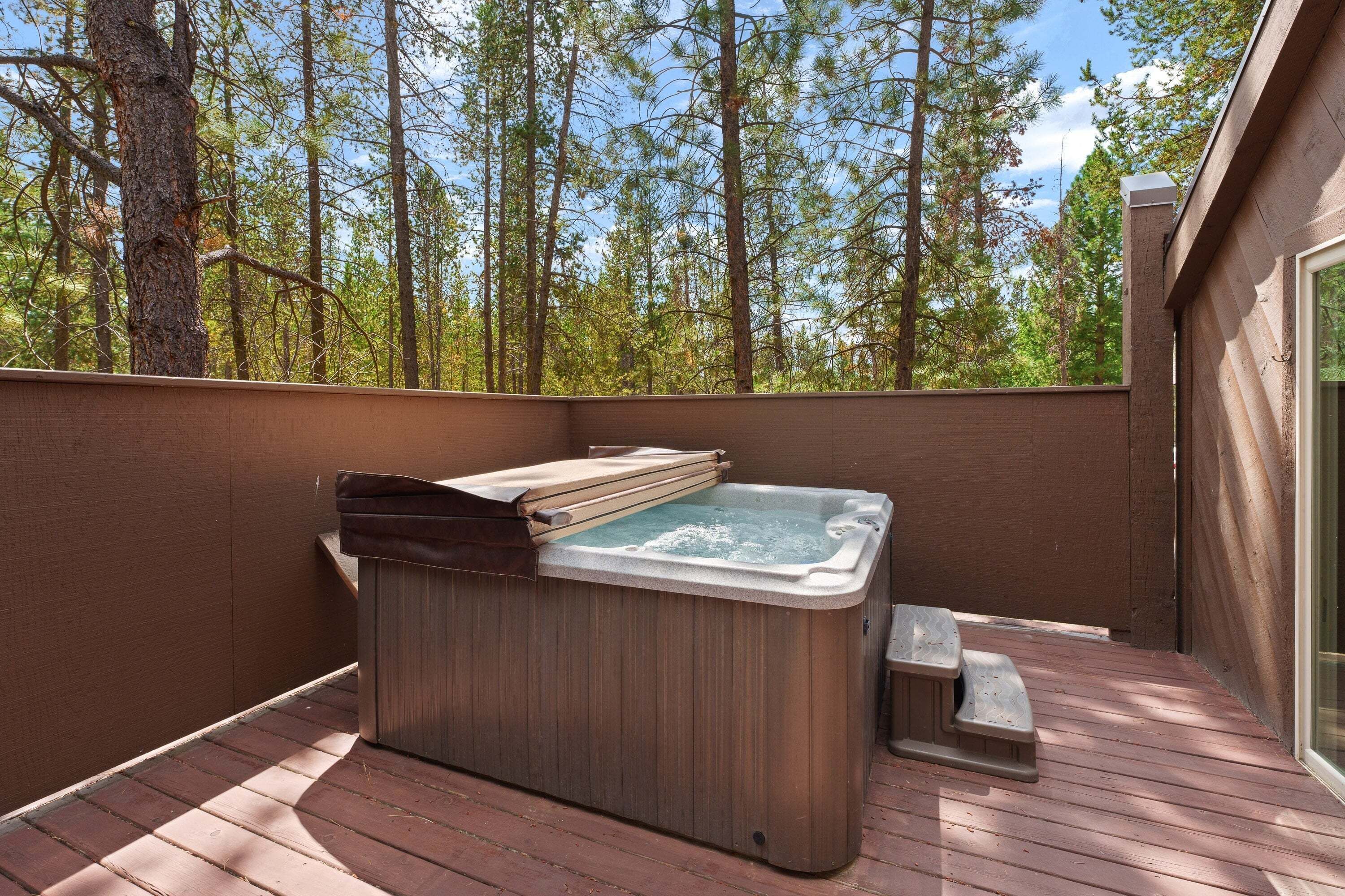 Un bain à remous sur une terrasse en bois, avec vue sur une forêt.