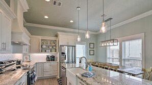 A kitchen with white cabinetry, a stainless steel refrigerator, and a granite countertop. - Easy Breezy 4 Bedroom Home (Port Bolivar)