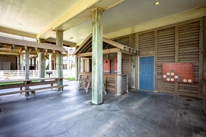 A covered outdoor area with a concrete floor, wooden benches, and a table. - Easy Breezy 4 Bedroom Home (Port Bolivar)