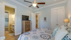 A bedroom with a bed, a ceiling fan, a dresser, and a television. - Easy Breezy 4 Bedroom Home (Port Bolivar)