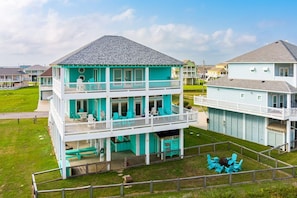 A two-story building with a balcony, a covered area with seating, and a fenced yard. - Gabriels Landing 5 Bedroom Home (Port Bolivar)