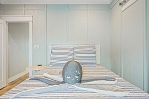 Une chambre à coucher avec un lit, des oreillers, une petite table ronde et une porte.