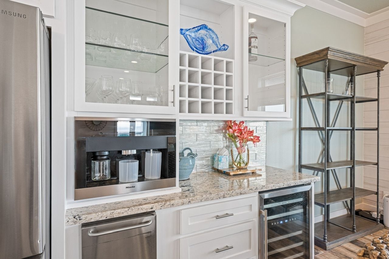A kitchen with a stainless steel refrigerator, a built-in microwave, and a coffee maker.