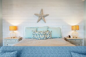 A bedroom with a wooden headboard, two bedside lamps, a starfish decoration, and patterned pillows. - Gabriels Landing 5 Bedroom Home (Port Bolivar)