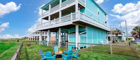 Een gebouw met twee verdiepingen, een balkon, een vuurkorf met stoelen en een gazon.