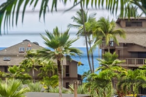 A beachfront property with multiple buildings, palm trees, and a view of the ocean. - Big Island Kanaloa At Kona 803 1 Bedroom Condo (Kailua-Kona)