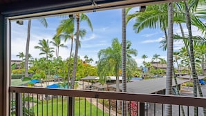 A view from a balcony with a railing, overlooking a pool area with palm trees and a clear sky. - Big Island Kanaloa At Kona 803 1 Bedroom Condo (Kailua-Kona)