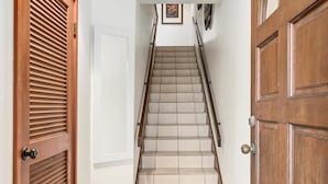 A staircase with a handrail, wooden doors, and a wall-mounted picture. - Big Island Kanaloa At Kona 803 1 Bedroom Condo (Kailua-Kona)