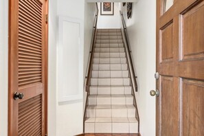 Eine Treppe mit Handlauf, Holztüren und einem an der Wand hängenden Bild.