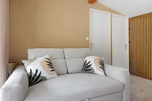 A room with a sofa, a door, and a wooden panel wall.