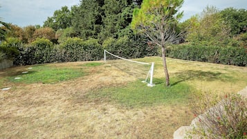 Une zone herbeuse avec un petit arbre et une clôture blanche.