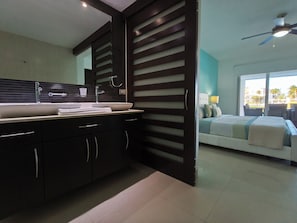 A modern bathroom with a large mirror, dark cabinetry, and a sink with a towel rack. - Ocean View Condo with Private Splash Pool Steps from the Beach at Mareazul (Playa Del Carmen)