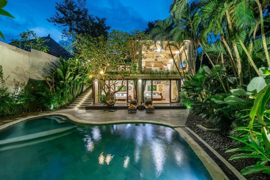Un resort con piscina, una escalera que lleva a un edificio y abundante vegetación.