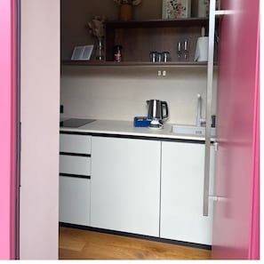 A kitchen with white cabinets, a coffee maker, and a blue box of utensils. - Apartment 'Ulivo' with Shared Pool, Wi-Fi and Air Conditioning (Prignano sulla Secchia)