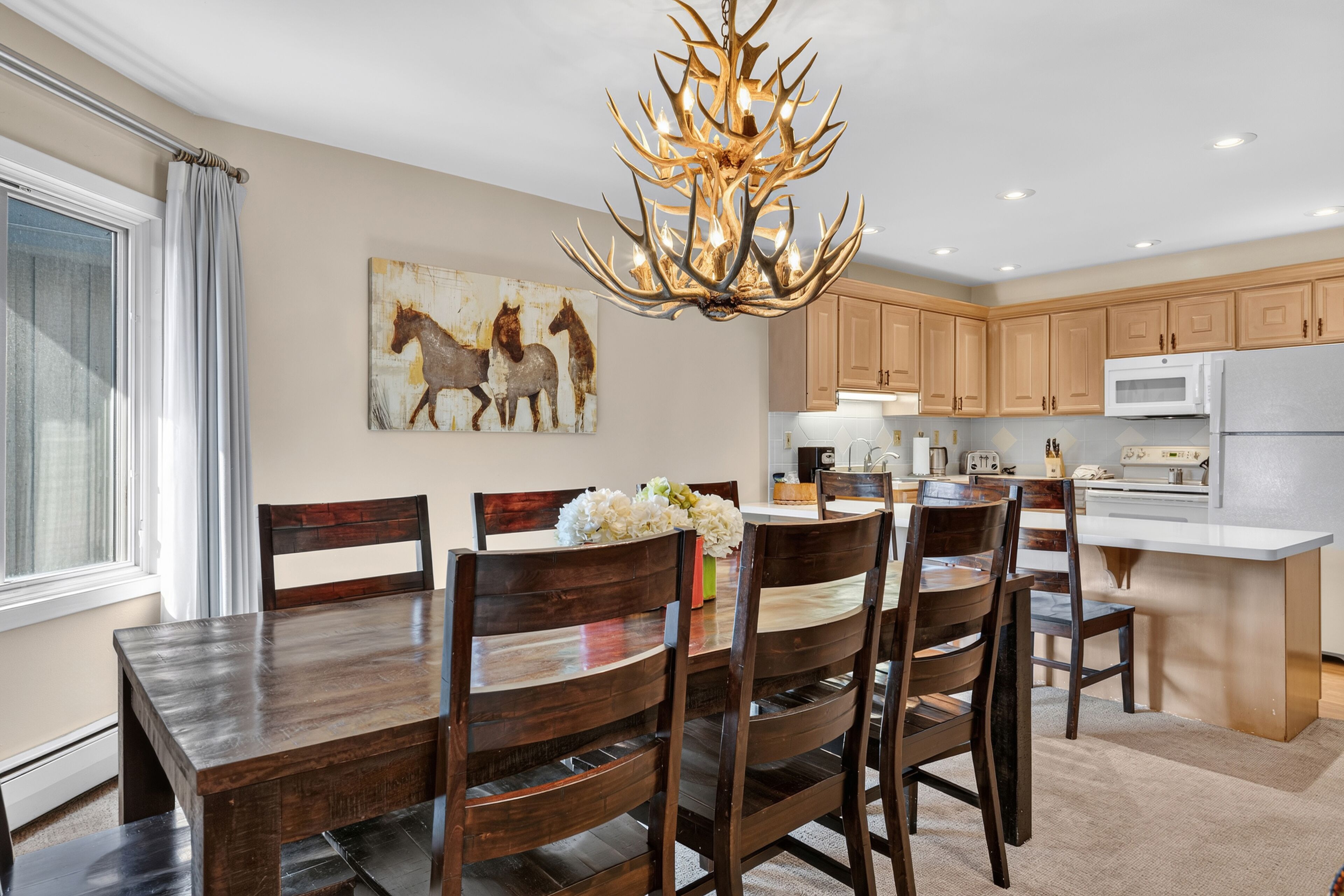 A modern kitchen with wooden cabinets, a central island, and a chandelier.