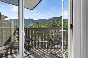 A balcony with a view of mountains, a table with chairs, and a glass door leading to a staircase. - Top-floor Ski Condo in Vail, walk to Gondola, W402 (Vail)
