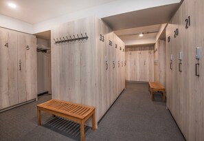 Ein Hotelgang mit Holfachschränken, nummeriert von 1 bis 21, einer Bank und einem Kleiderständer.