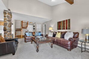 A spacious living room with a stone pillar, leather furniture, and a modern chandelier. - Top-floor Ski Condo in Vail, walk to Gondola, W402 (Vail)
