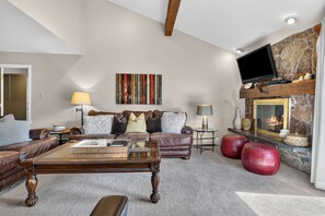 A living room with a fireplace, leather sofas, a flat-screen TV, and a decorative wall piece. - Top-floor Ski Condo in Vail, walk to Gondola, W402 (Vail)